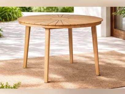Round wooden table with a sunburst slat top on a woven rug
