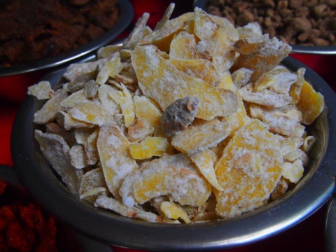 Dried mango pieces with a white coating in a metal bowl
