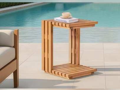 C-shaped slatted wooden side table with a book and cup beside a pool