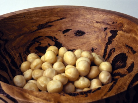 Macadamia kernels in a brown wooden bowl