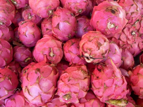 A heap of pink dragon fruits filling a market stall