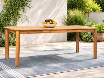 Rectangular wooden dining table with a fruit bowl on an outdoor rug