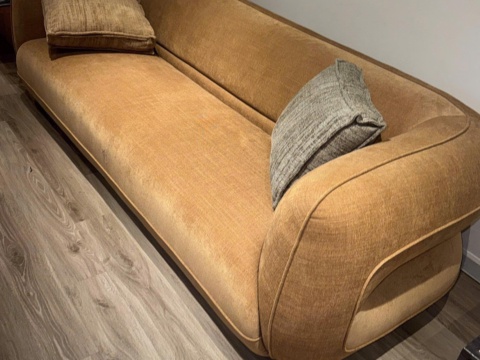 Long ochre sofa with a curved back on a wooden floor