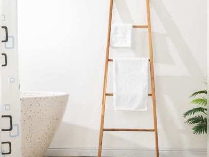 Wooden ladder leaning on a wall with two white towels in a bathroom