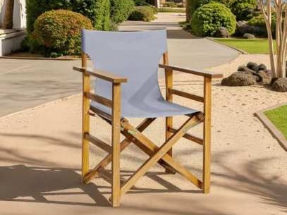 Wooden director chair with a grey-blue fabric sling on a gravel path
