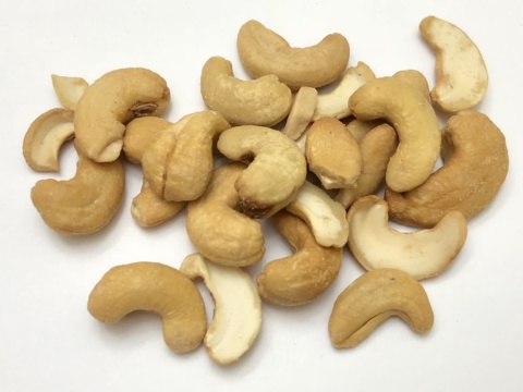 Light golden roasted cashew kernels scattered on a white background