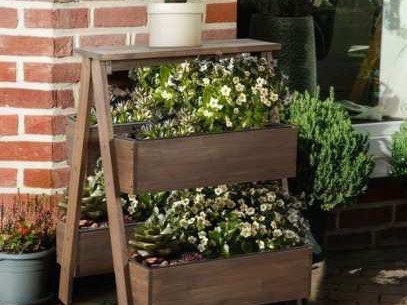 A-frame wooden flower stand with white blooms against a red brick wall