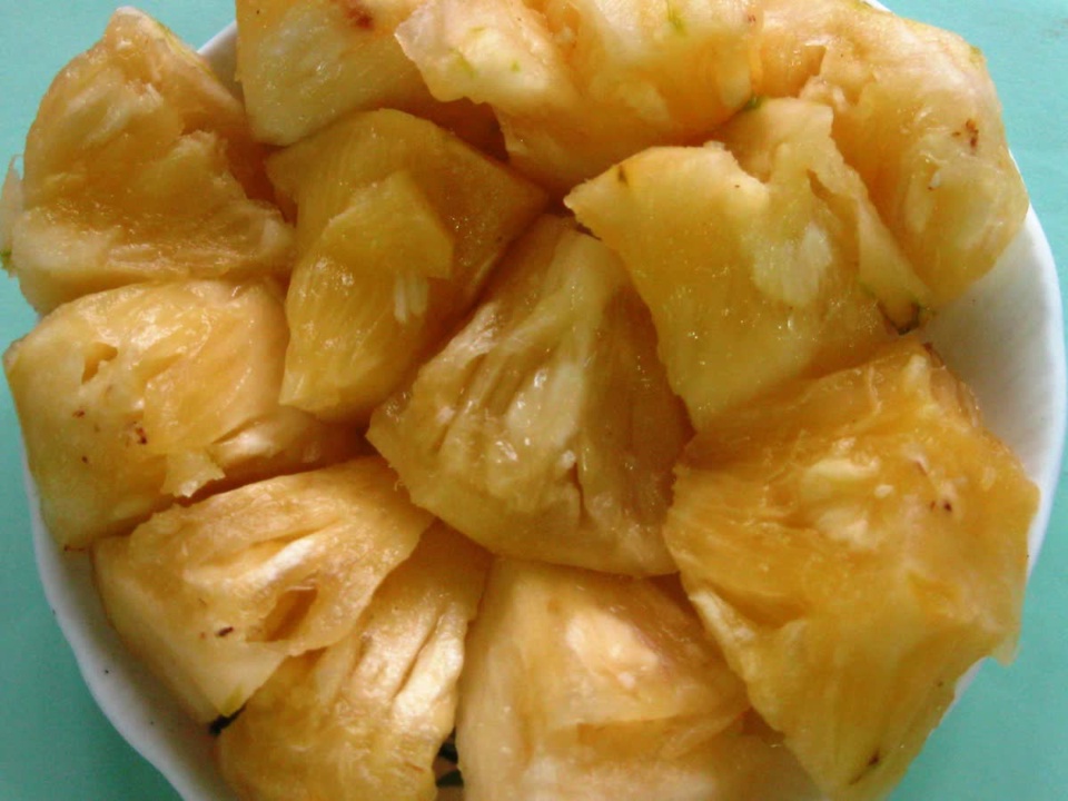 Yellow pineapple pieces filling a white bowl