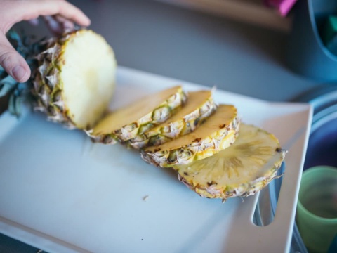 A pineapple cut into round slices on a board