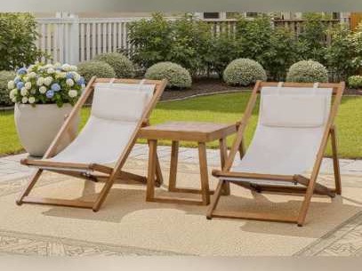 Two reclining wooden sling chairs with a small table on a garden rug