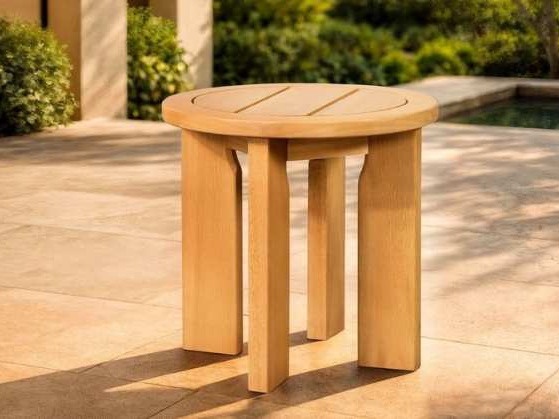 Round wooden side table with thick legs on a stone terrace