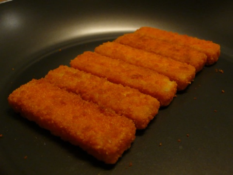 Six breaded fish sticks lined up in a pan