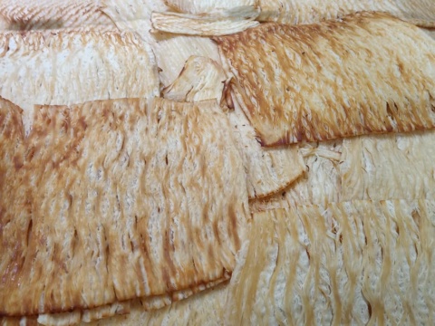 Flat dried squid fillets stacked, light brown surface