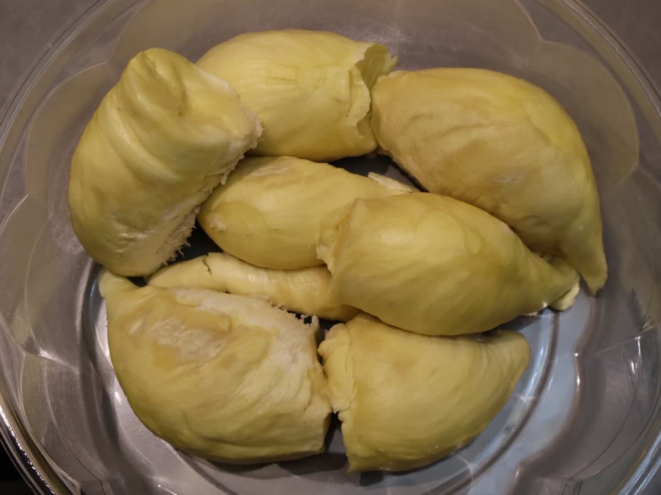 Pale yellow durian pulp segments in a clear plastic tray
