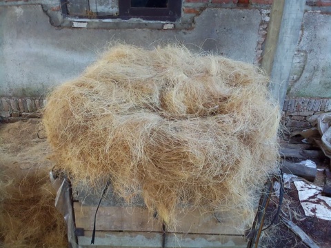 A loose heap of coir fibre piled on a cart in a yard