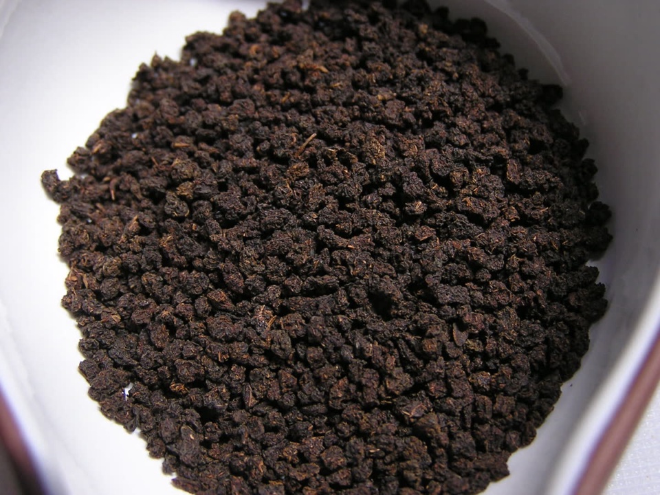 Dark black CTC tea granules in a white bowl