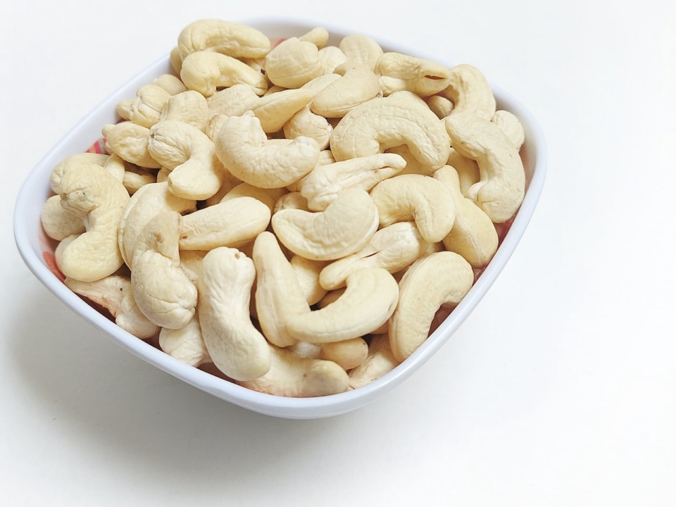 Whole white cashew kernels in a white bowl
