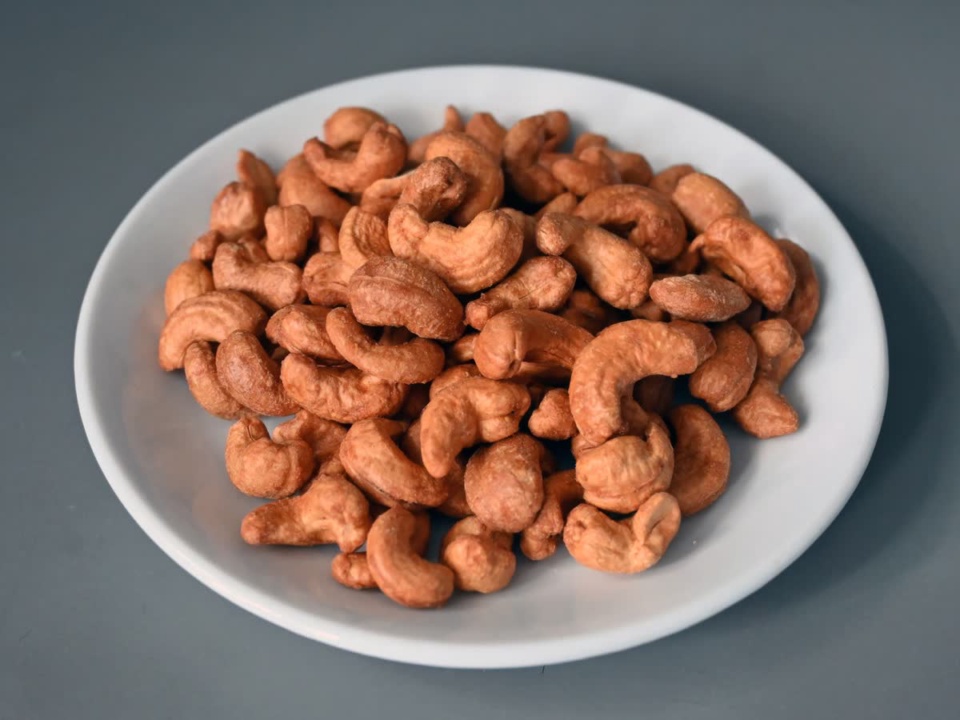 Orange red roasted cashews on a white plate