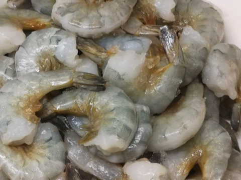 Headless shell-on shrimp piled together with grey-green shells and intact tails