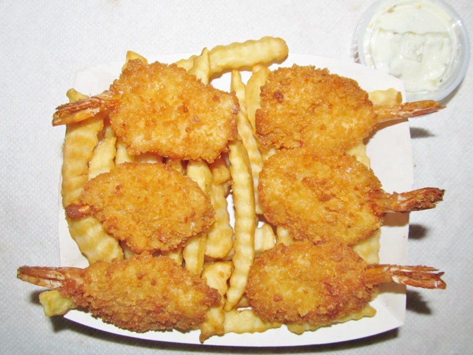 Golden breaded shrimp with tails arranged over French fries