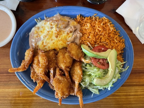 Golden breaded shrimp with tails on a blue plate