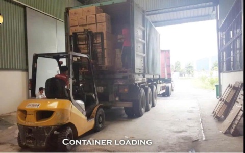Xe nâng xếp thùng carton vào container trên xe đầu kéo, có chữ Container loading