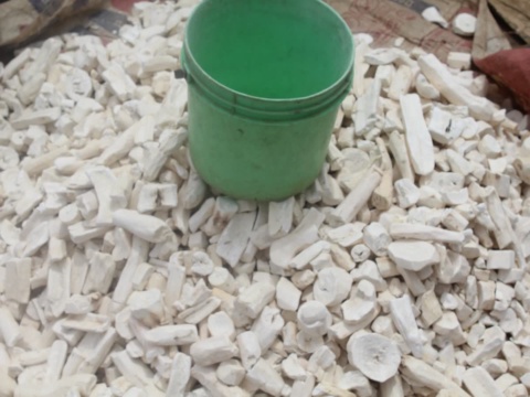 Sắn khô miếng nhỏ màu trắng cạnh xô nhựa xanh